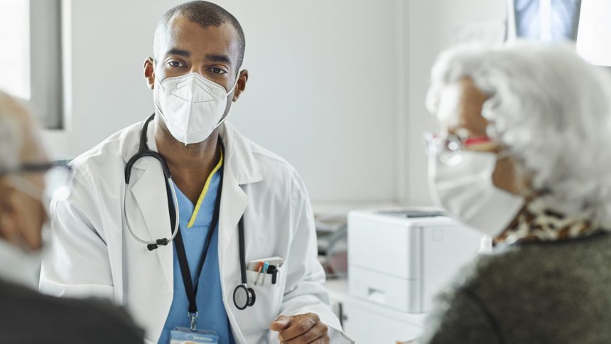 Doctor speaking with older couple during COVID-19 pandemic