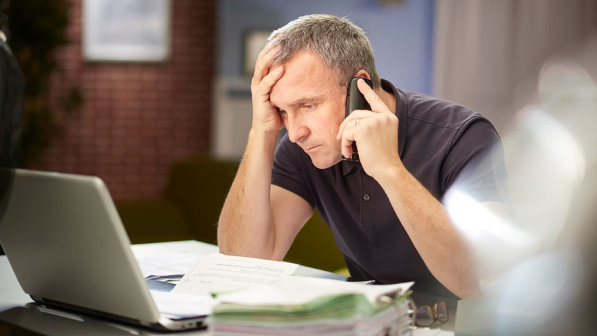 A stressed nursing home operator looks at a computer while on the phone